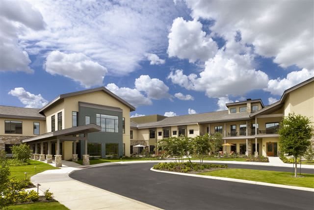 A modern building with a curved driveway under a partly cloudy sky.