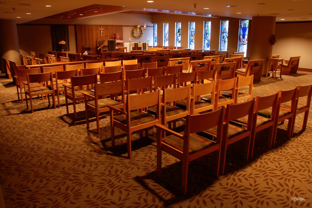 Interior view of a chapel with wooden chairs and natural lighting.