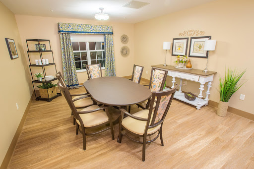 A cozy dining room featuring an oval table and upholstered chairs, complemented by warm lighting and soft color tones.