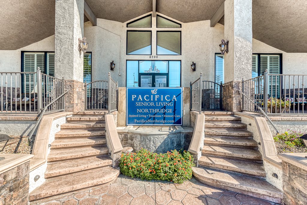 The entrance to Pacifica Senior Living, featuring a welcoming sign and elegant staircases.