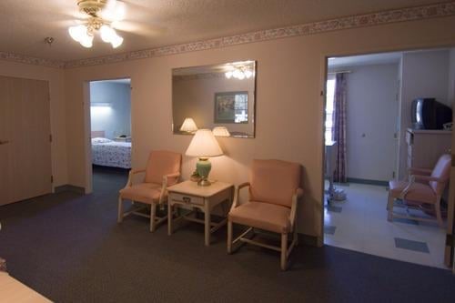 A cozy hotel room interior featuring a pair of chairs with a table and lamp, along with a mirror on the wall.