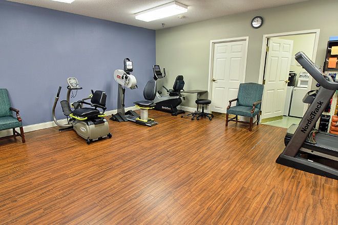 A small exercise room with various fitness equipment and wooden flooring.