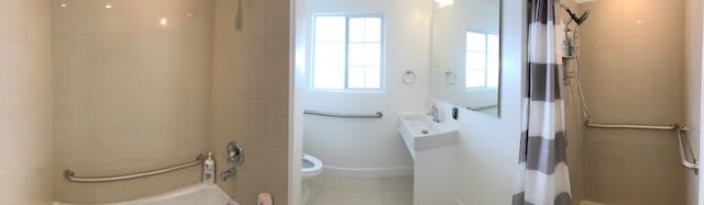 A clean, white bathroom with a toilet, sink, and a window.