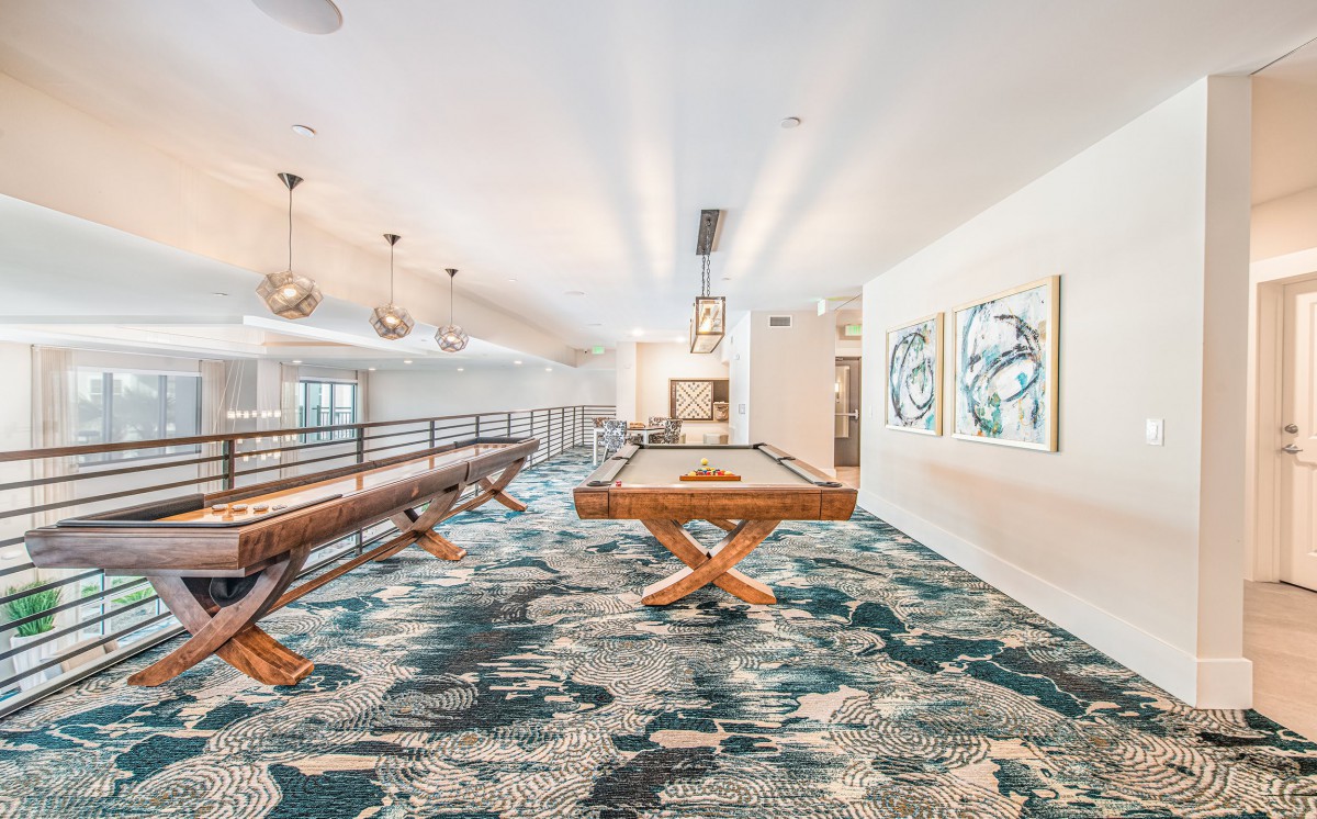 A modern game room featuring a pool table, stylish lighting, and contemporary carpet design.