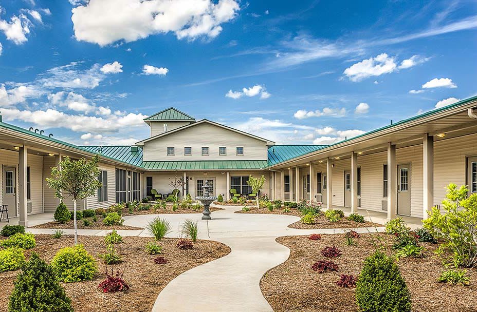 A beautiful building with a courtyard garden under a blue sky with clouds.