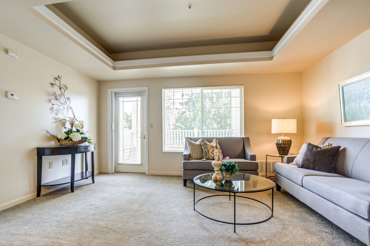 A bright and elegantly decorated living room with comfortable sofas, a glass coffee table, and modern lighting.