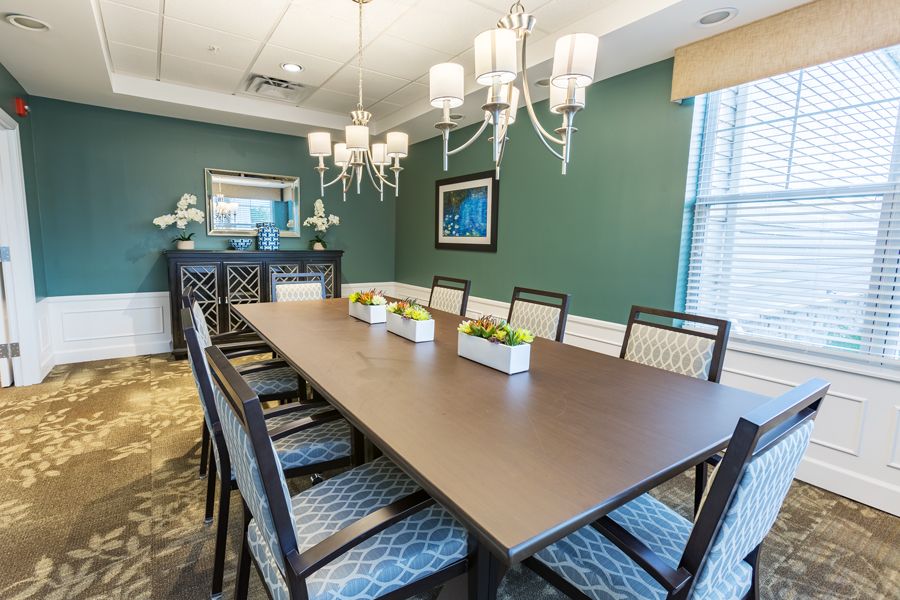 A beautifully decorated dining room with a long table surrounded by chairs and elegant chandeliers.