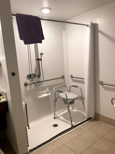 An accessible shower setup featuring grab bars and a shower chair for safety and convenience.