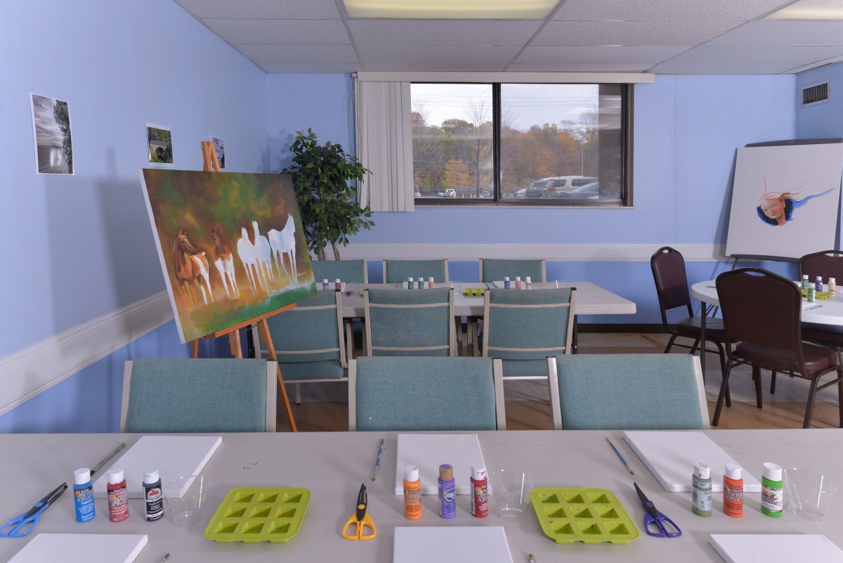 A classroom setup with painting supplies and canvases arranged for an art class.
