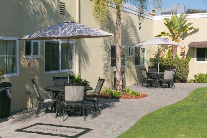 An outdoor patio area with tables, chairs, and umbrellas near a building.