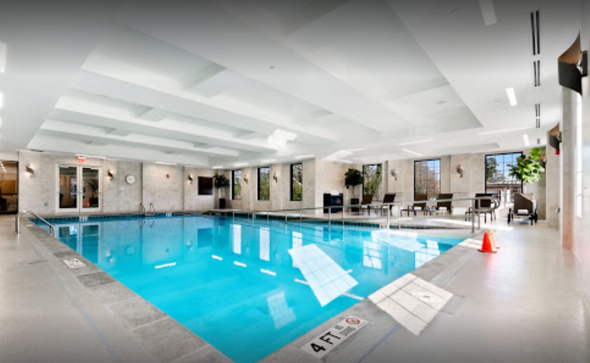 An inviting indoor swimming pool with seating areas and bright lighting.