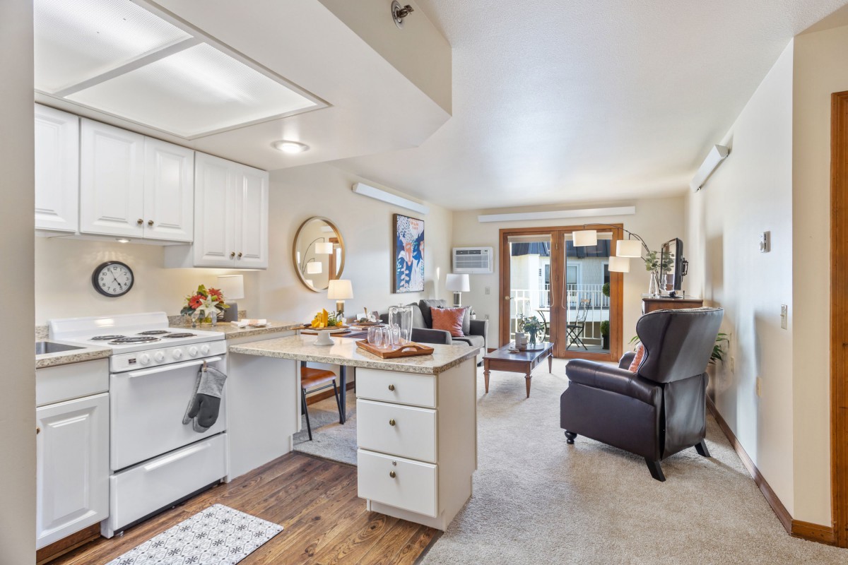 A cozy open-space kitchen and living room with modern furniture and bright lighting.