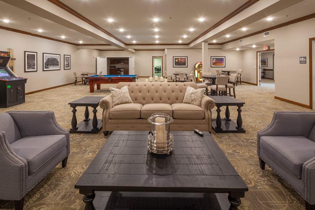 A spacious and well-lit living room featuring comfortable seating and a pool table.