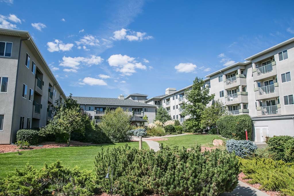 Beautiful residential apartment complex surrounded by lush gardens and a clear blue sky.
