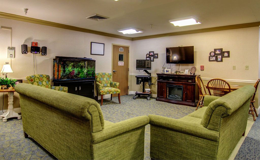 A cozy living room with sofas, a fish tank, and a TV on the wall.