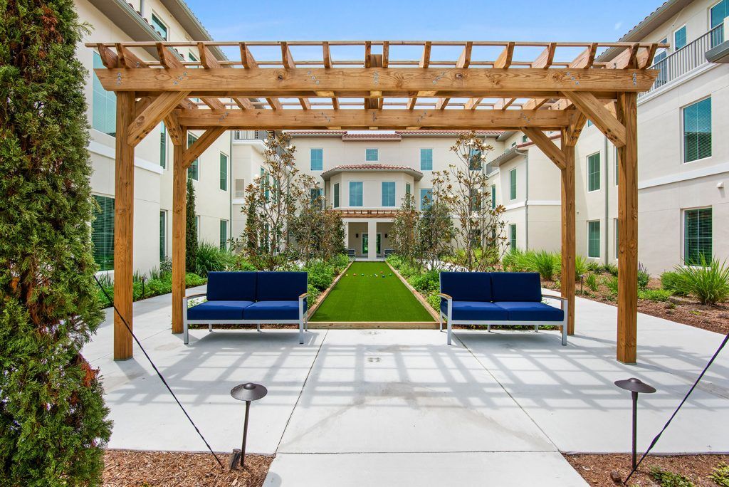 A beautifully landscaped garden with a pergola and benches, leading to a building facade.