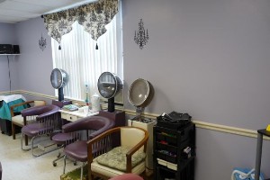 An interior view of a hair salon with dryers and chairs arranged in a neat line.