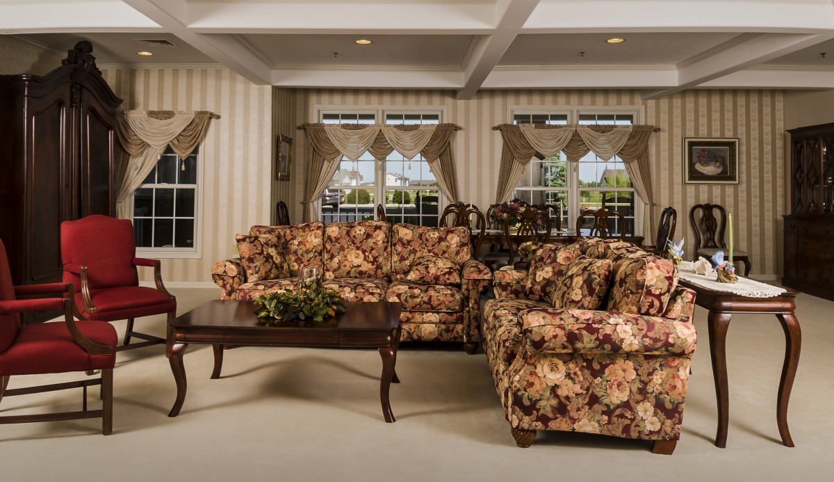 A traditional living room featuring floral-patterned sofas and a wooden coffee table set against striped wallpaper.
