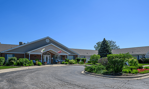 A well-maintained suburban building with lush landscaping and a circular driveway on a clear day.