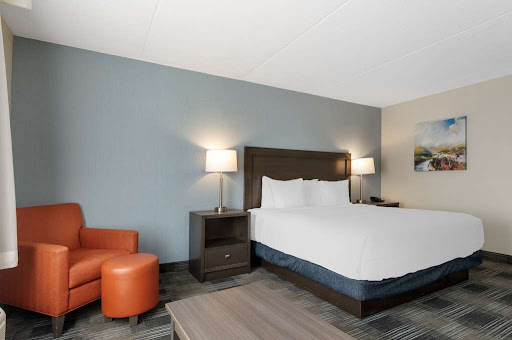 A modern hotel room featuring a comfortable bed, stylish chair, and warm lighting.
