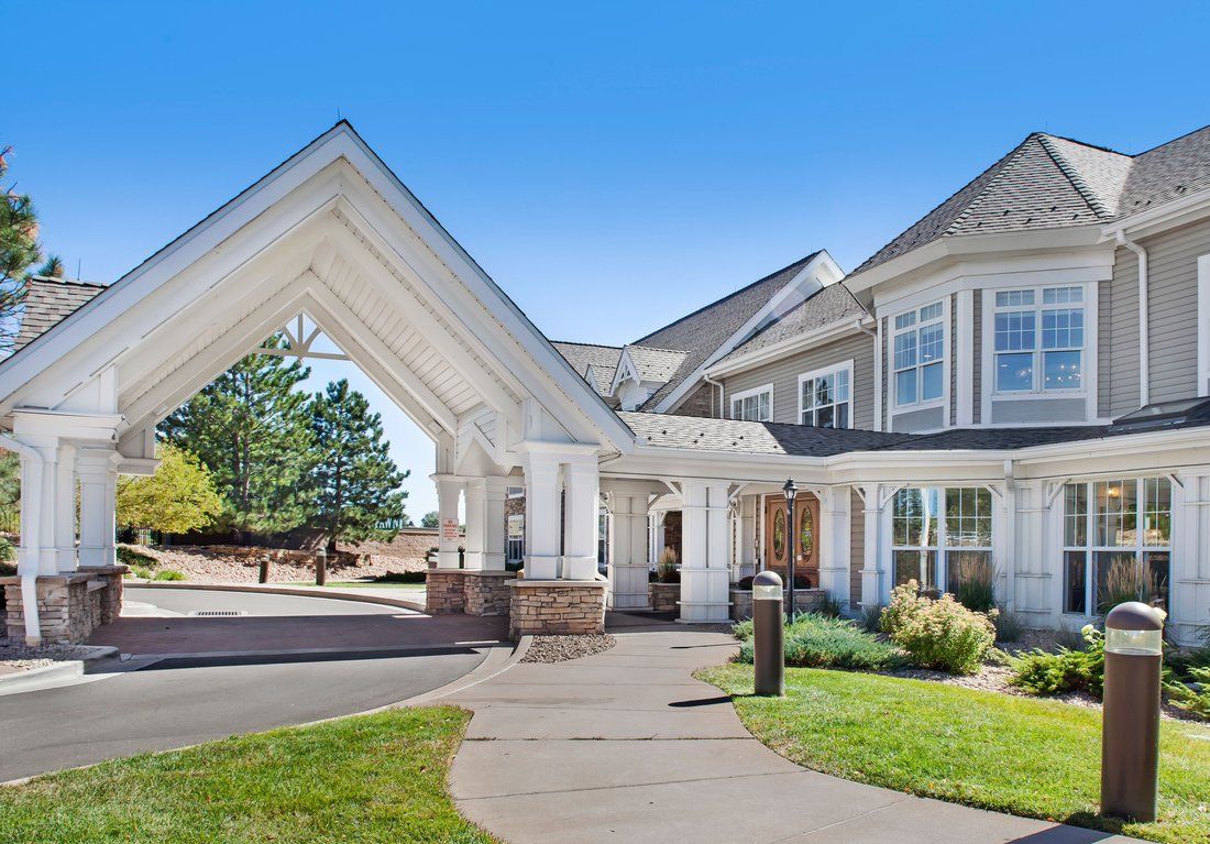 A large residential building with a covered entrance and landscaped surroundings.
