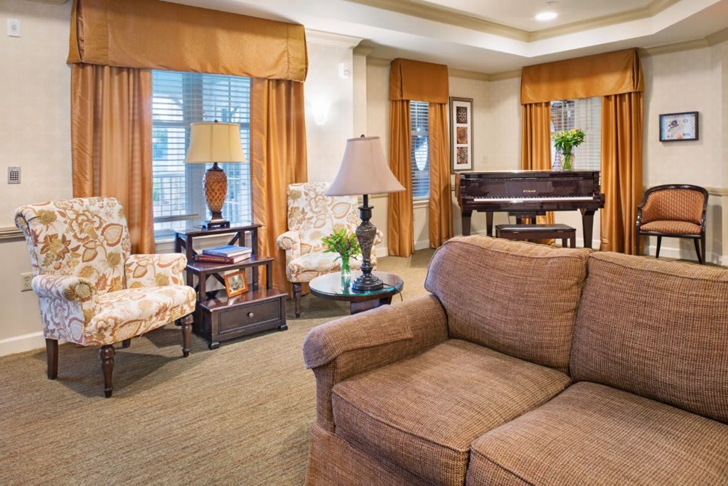 A cozy living room featuring a plush sofa, elegant curtains, and a grand piano.