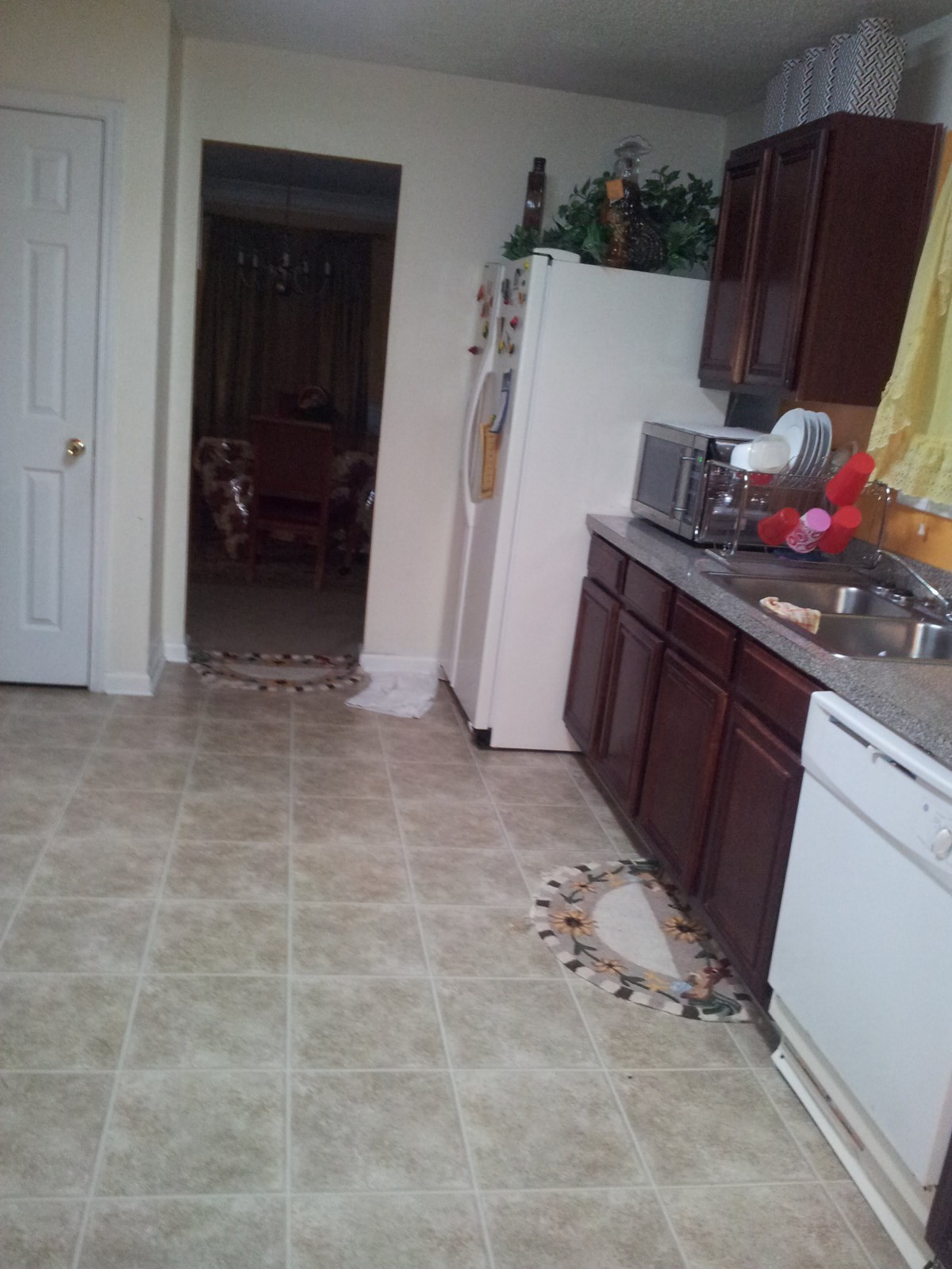 A kitchen interior with wooden cabinets, appliances, and tiled flooring.
