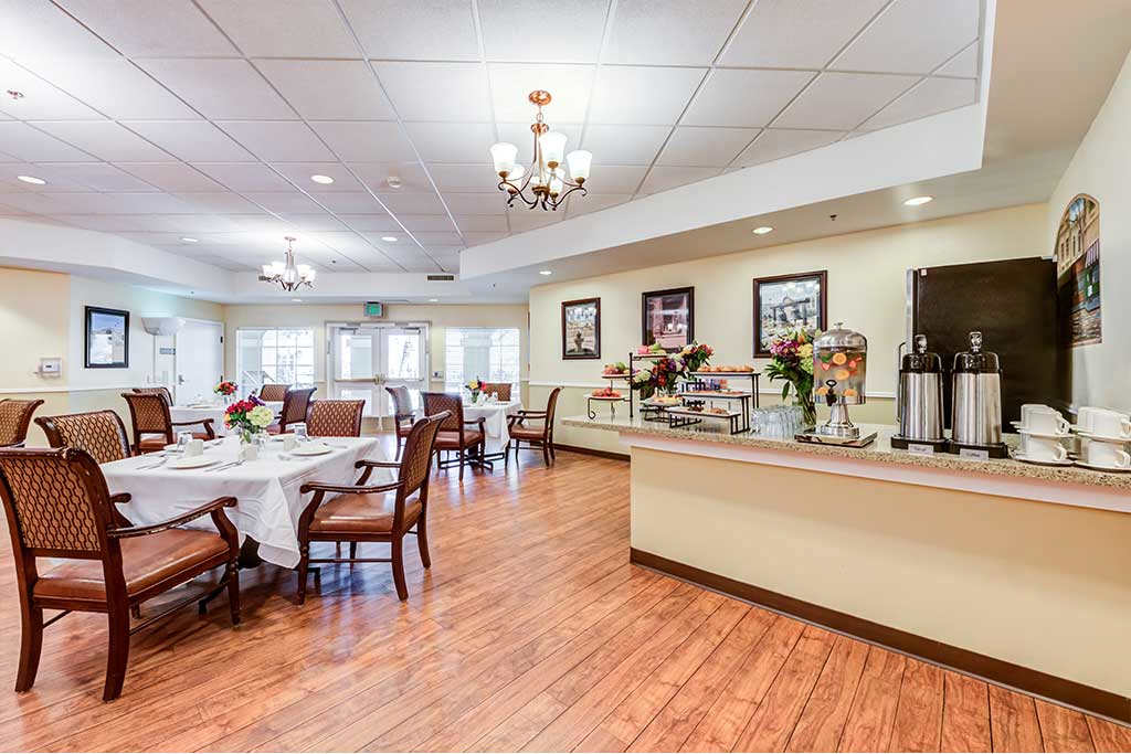 A spacious dining room with elegantly set tables and a serving area.