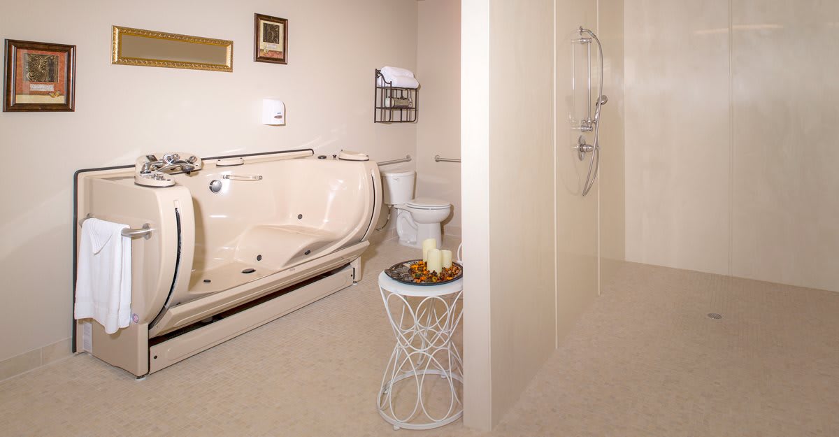 A modern bathroom featuring a jacuzzi tub, toilet, and walk-in shower with decorative candles on a side table.