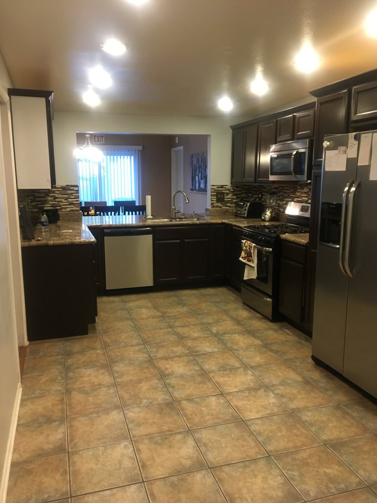 A modern kitchen with dark cabinets and stainless steel appliances.