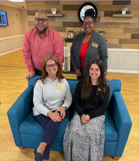 A group of four professionals posing together in a modern office environment.