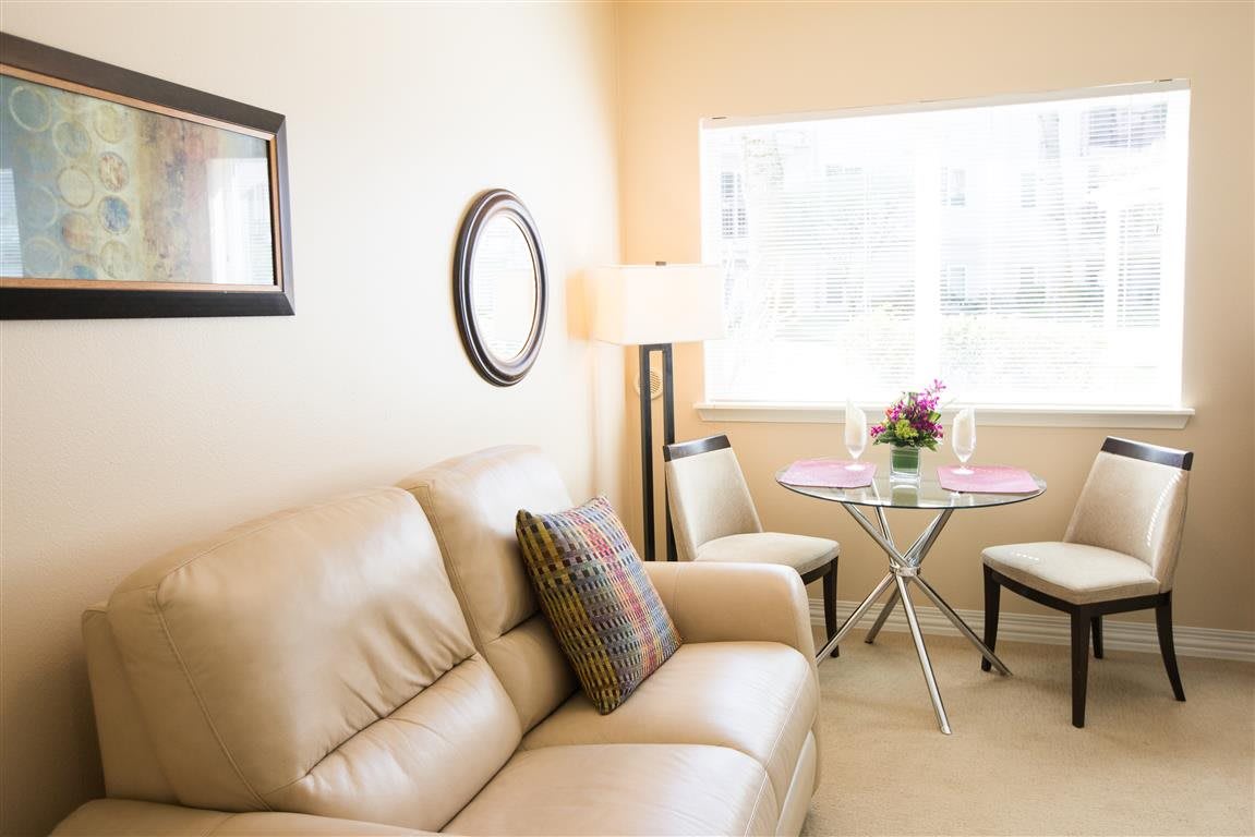 A cozy, modern living room with a beige sofa and round dining area.