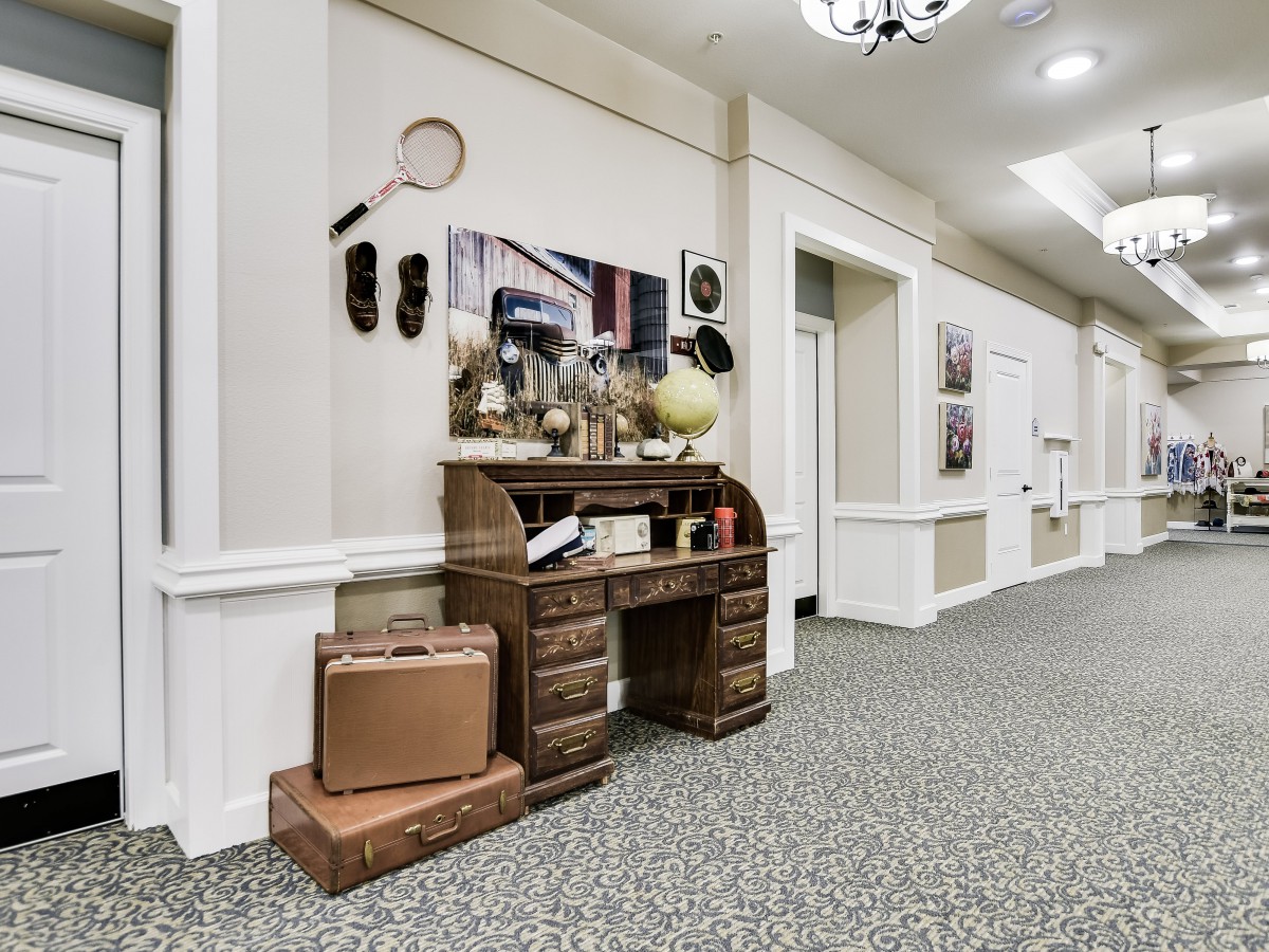 A vintage-themed hallway with a decorative wooden desk and old-fashioned luggage.