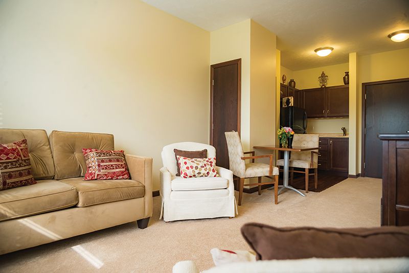 A cozy living room featuring a sofa, armchairs, and an open kitchen area.