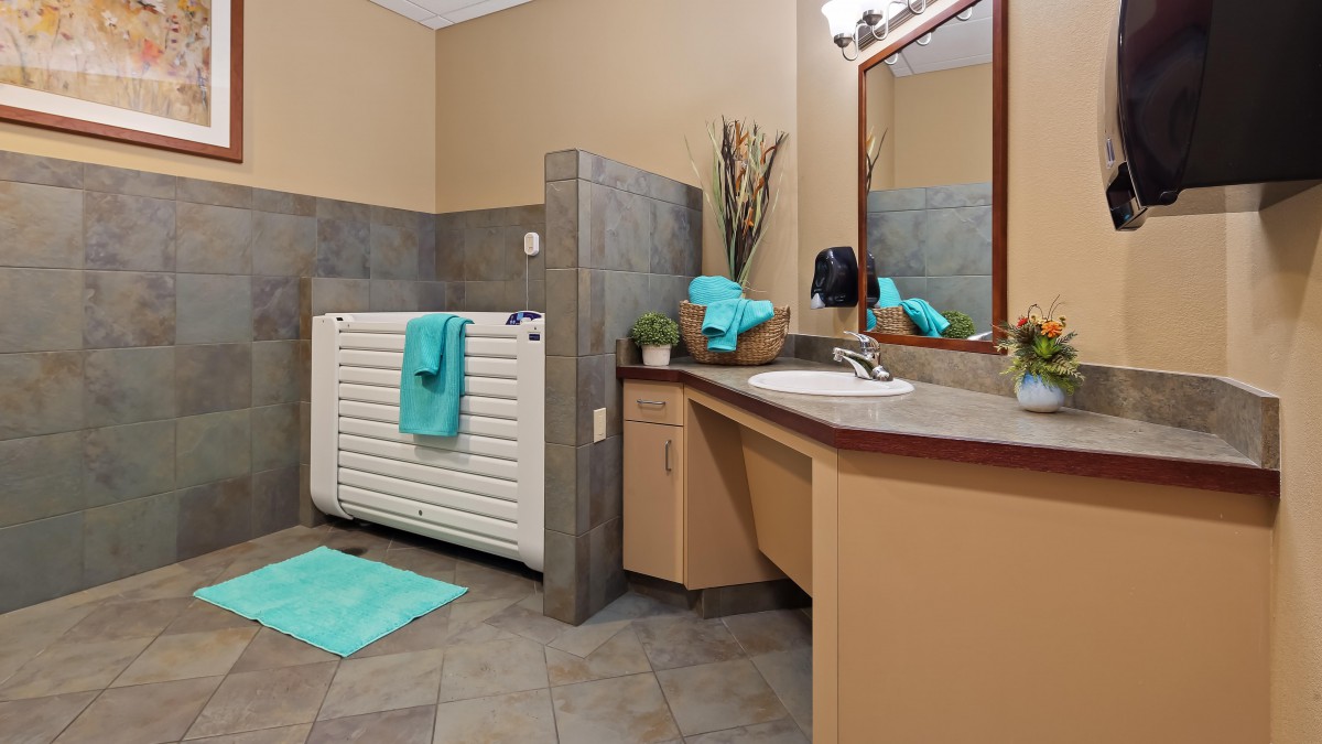 A modern bathroom with a sink, mirror, and teal accents.