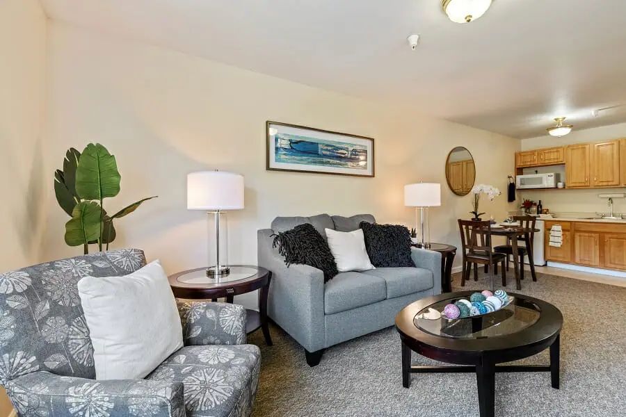 A cozy living room with a sofa, armchairs, coffee table, and dining area.