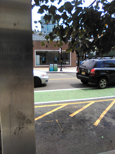 A view of a city street featuring parked cars and a green bike lane.