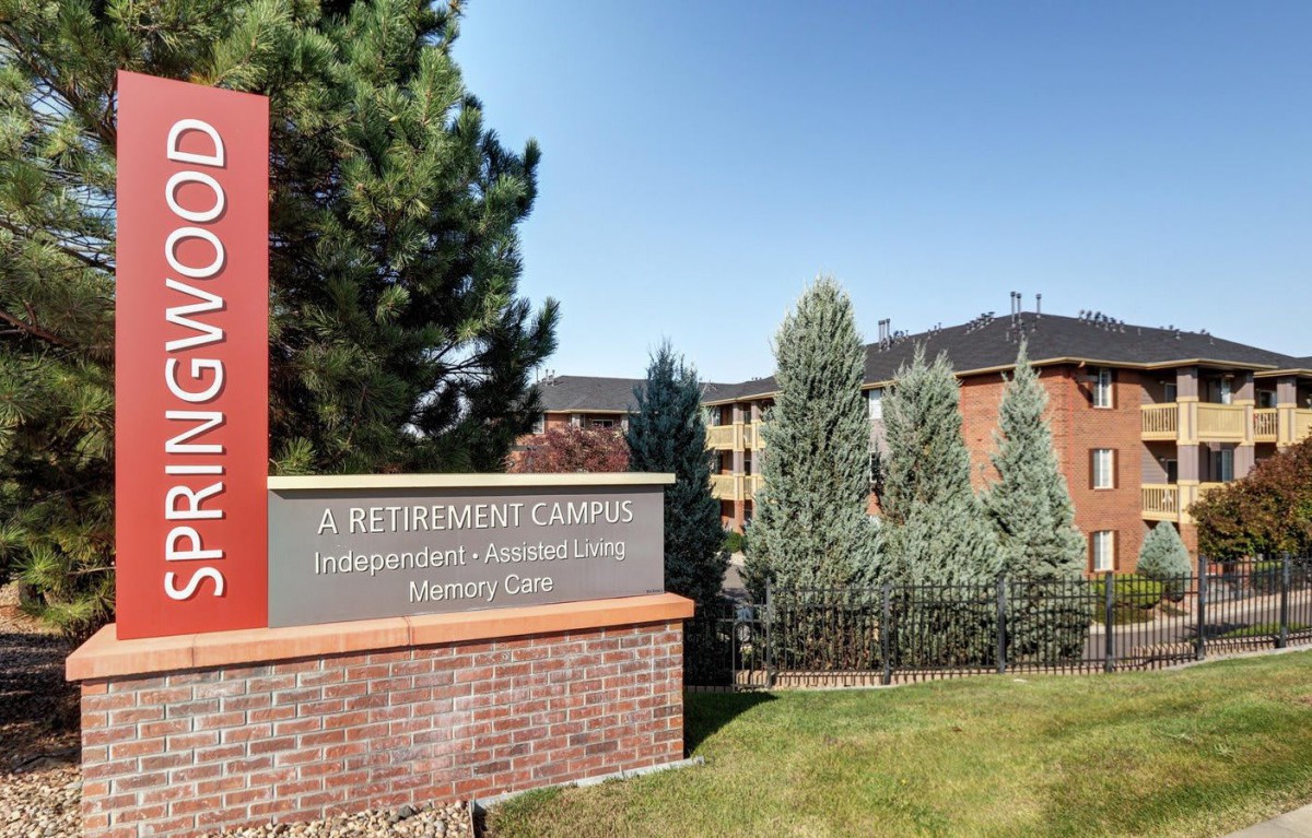 Entrance sign for a retirement community with surrounding greenery and buildings in the background.