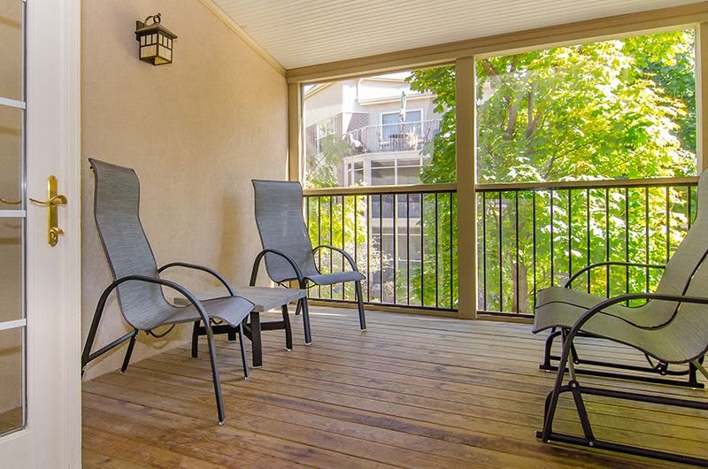 A cozy porch with comfortable chairs overlooking a lush, green landscape.