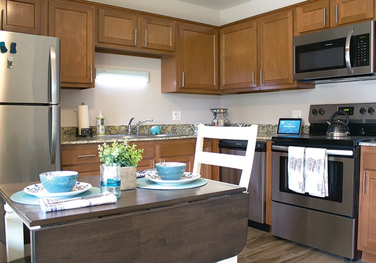 A modern kitchen with wood cabinets, stainless steel appliances, and a cozy dining area.
