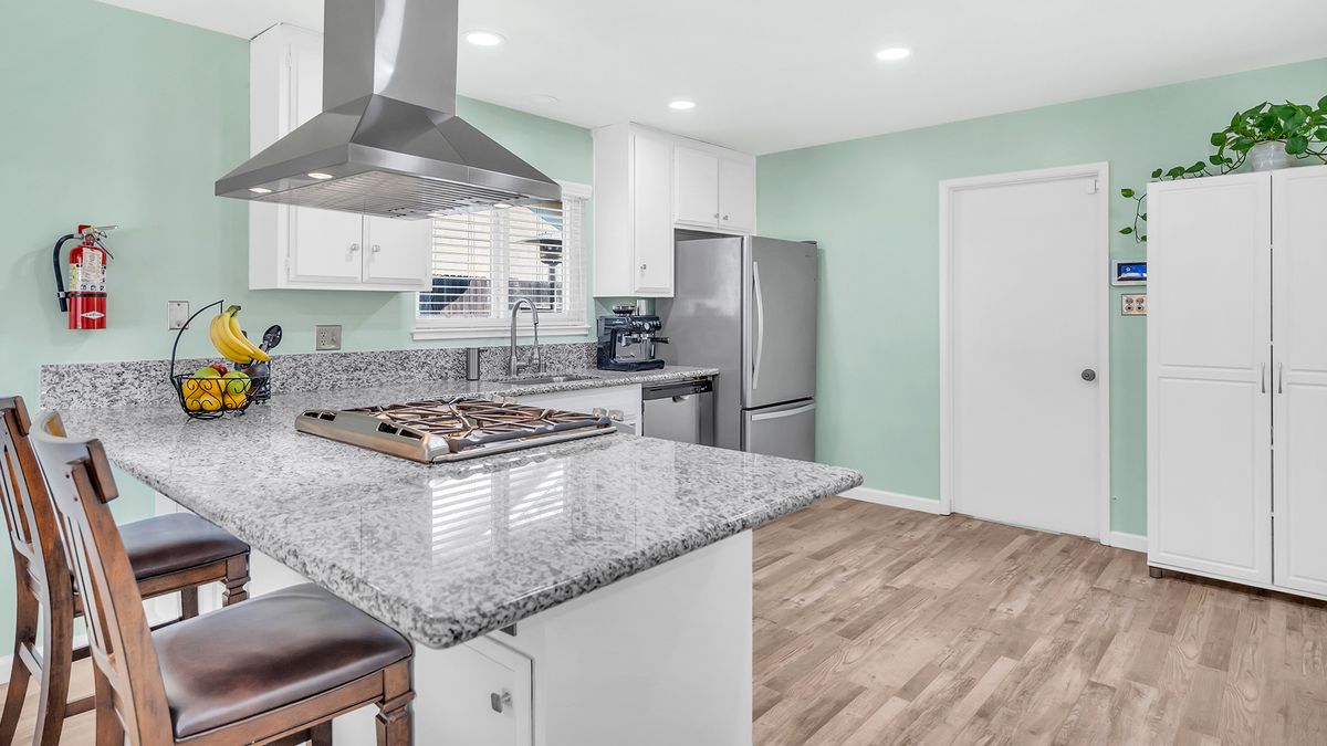 A modern kitchen with stainless steel appliances, granite countertops, and wood flooring.