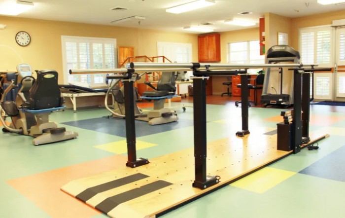 A rehabilitation room with parallel bars and exercise equipment.
