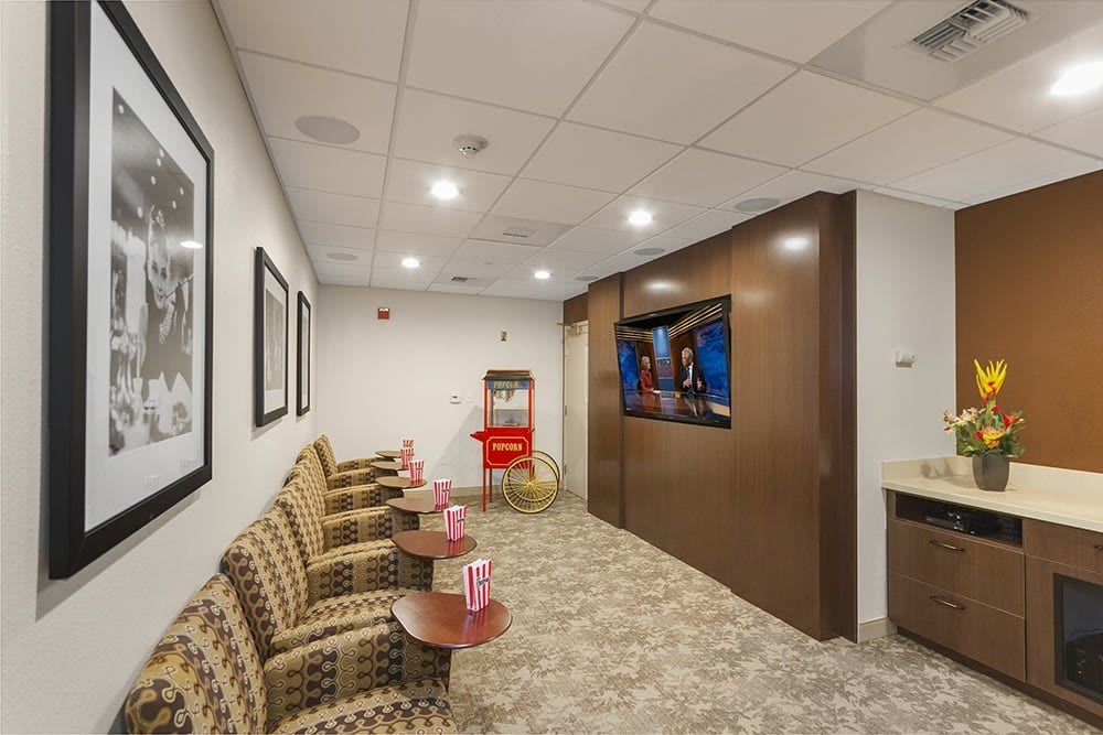 A cozy waiting room featuring comfortable seating, a television, and a popcorn machine.