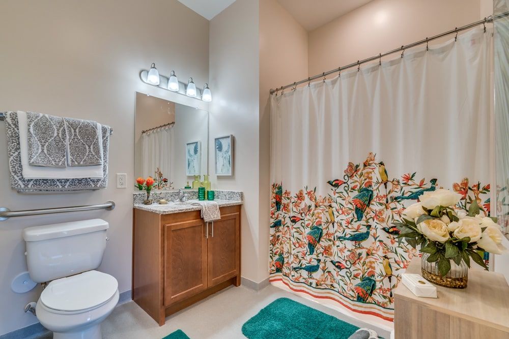 A neatly decorated bathroom with a colorful shower curtain and teal accents.