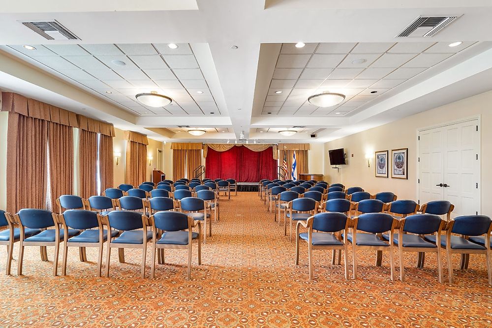 A well-equipped conference room with rows of chairs facing a small stage.