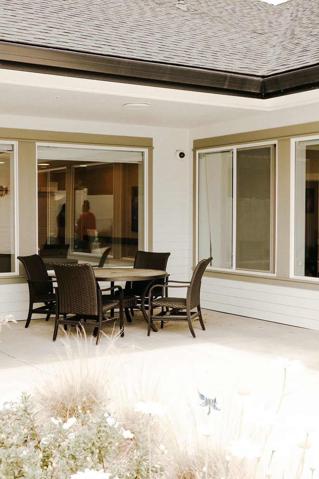 A modern patio area featuring a table with chairs surrounded by large windows.