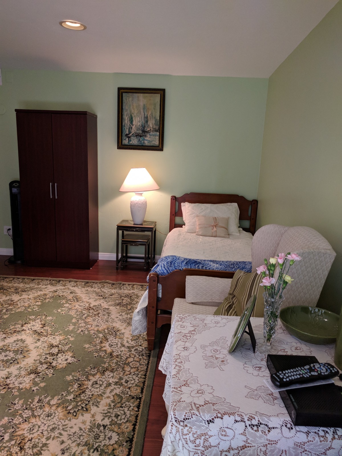 A cozy bedroom with a single bed, lamp, and wardrobe.