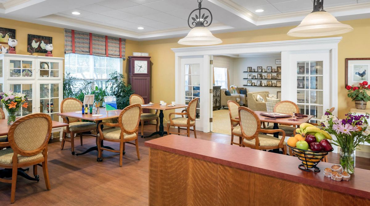 A cozy dining room with elegant chairs and tables, featuring warm lighting and wooden flooring.