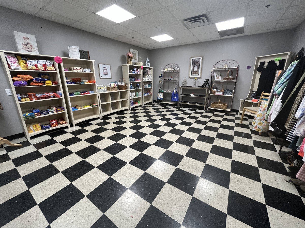 A retail room with checkered flooring and shelves showcasing various items.