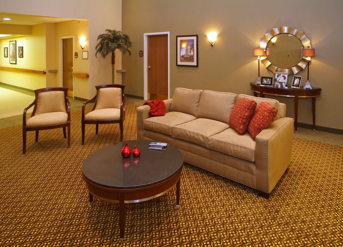 A cozy living room with a beige sofa, two chairs, and a round coffee table adorned with red accents.